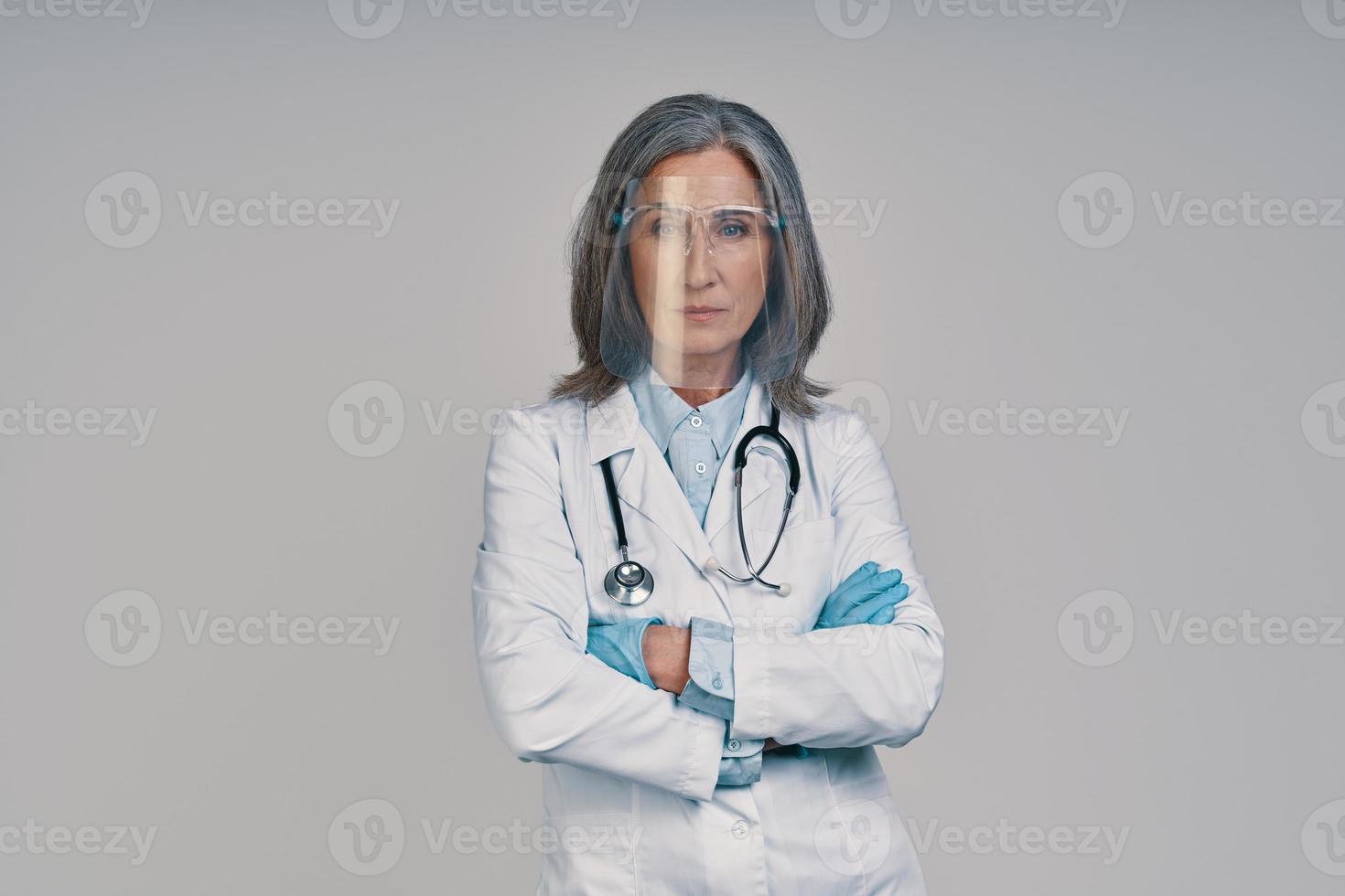 volwassen mooi vrouw dokter in gezicht schild houden armen gekruiste foto