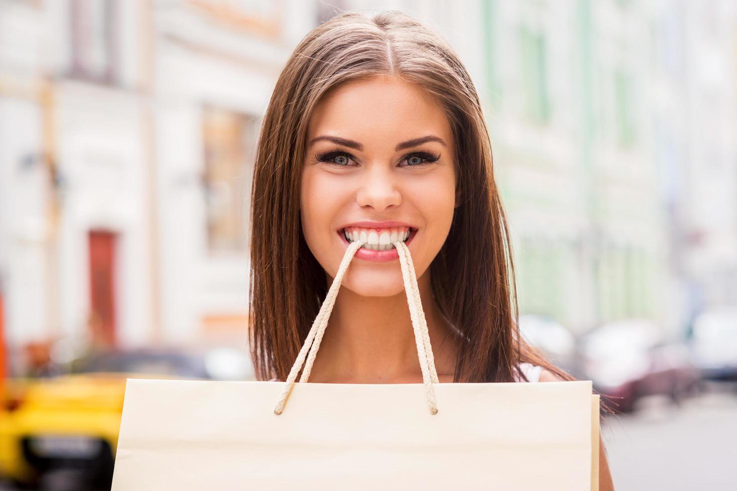 speels winkelverslaafd. mooi jong vrouw draag- boodschappen doen zak door tanden en glimlachen foto