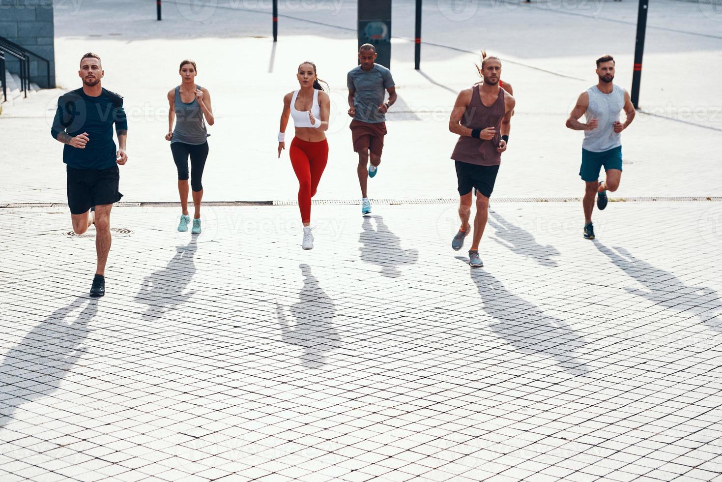 vol lengte top visie van mensen in sport- kleding jogging terwijl oefenen Aan de trottoir buitenshuis foto