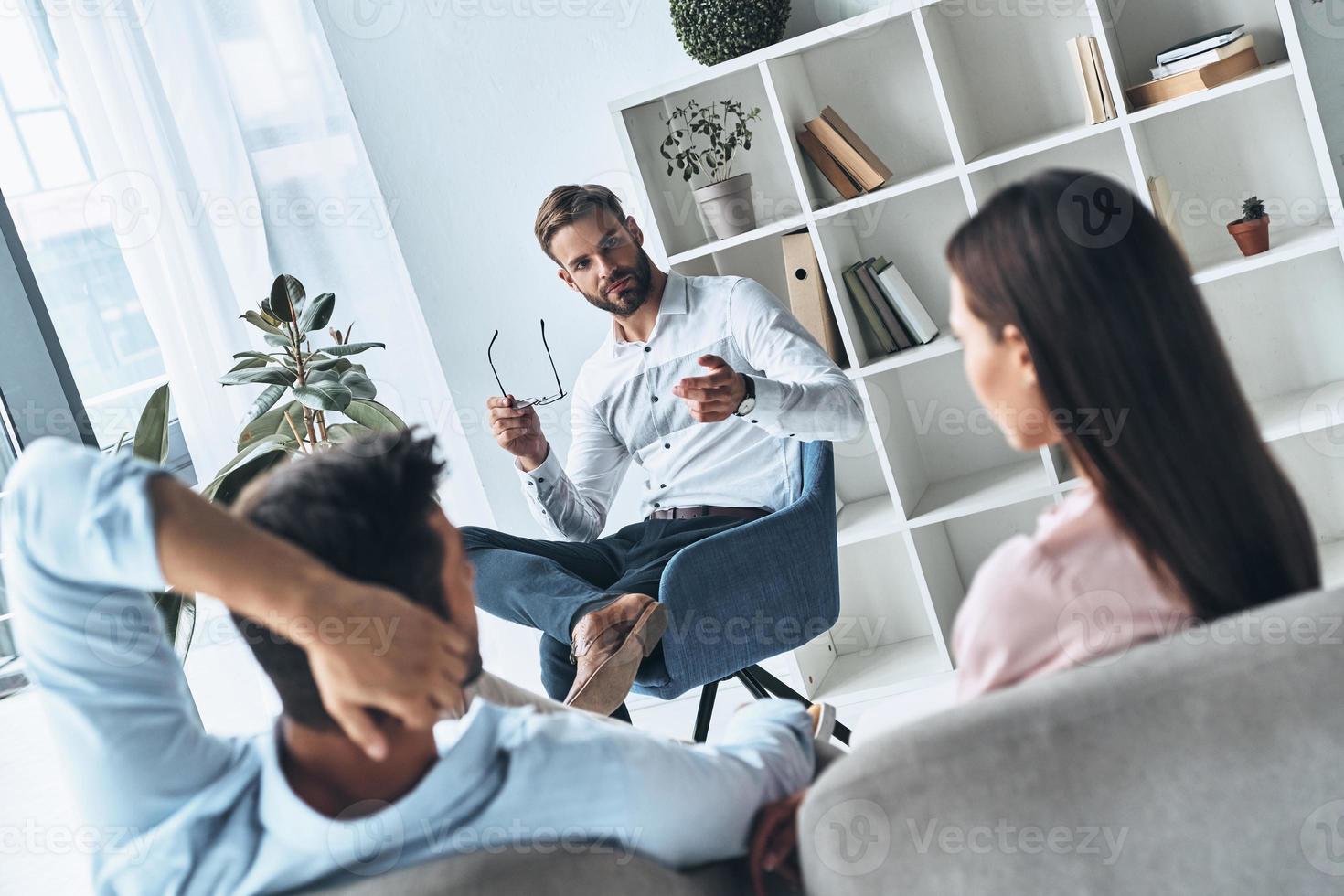 wij zullen maken het werk. jong getrouwd paar luisteren naar psycholoog terwijl zittend Aan de behandeling sessie foto