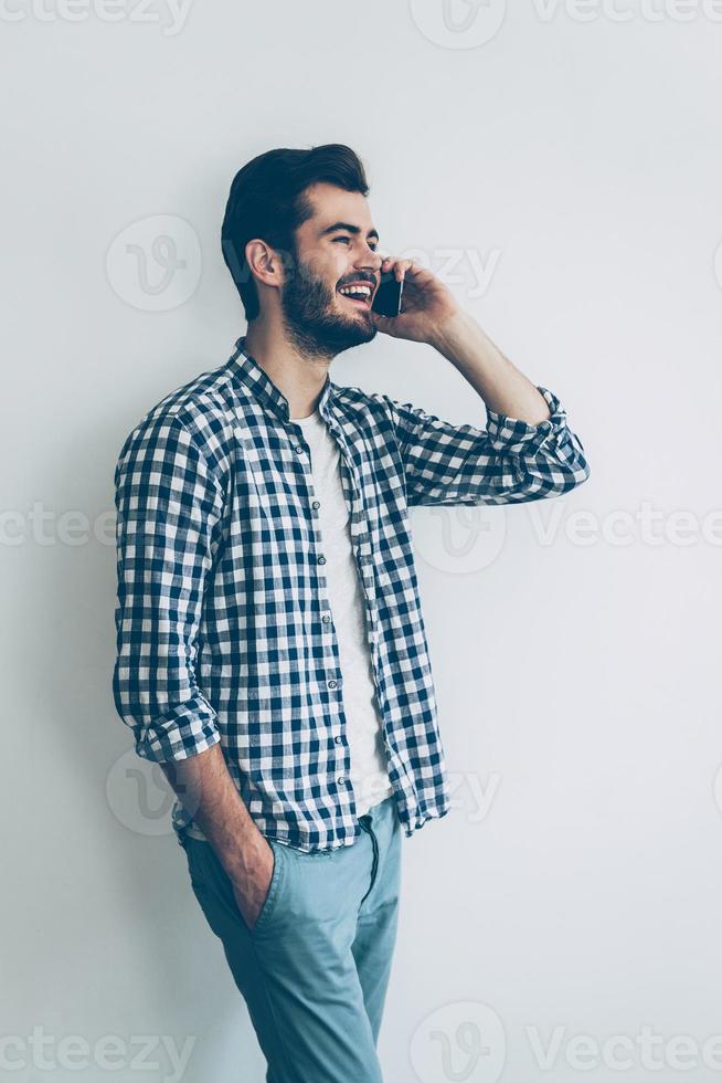 sharing mooi zo nieuws. gelukkig jong Mens pratend Aan mobiel telefoon en glimlachen foto