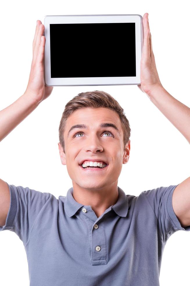 kopiëren ruimte Aan zijn tablet. gelukkig jong Mens Holding digitaal tablet op zijn hoofd en glimlach terwijl staand geïsoleerd Aan wit achtergrond foto
