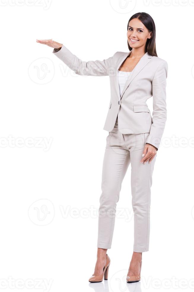 tonen maat. vol lengte van zelfverzekerd jong zakenvrouw in pak tonen grootte terwijl staand tegen wit achtergrond foto