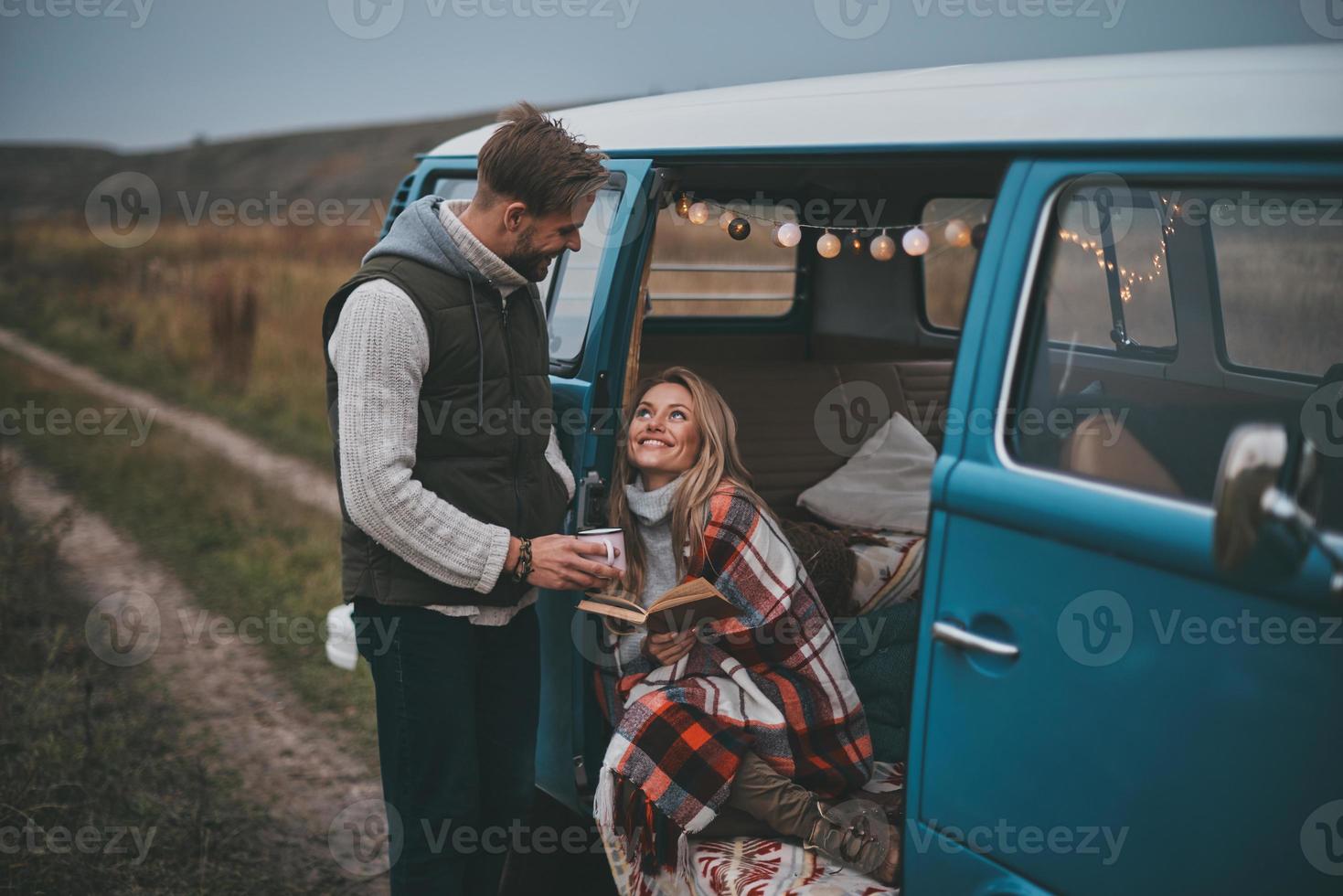 gemakkelijk vreugde van wezen in liefde. knap jong Mens geven een mok naar zijn vriendin terwijl genieten van hun weg reizen foto