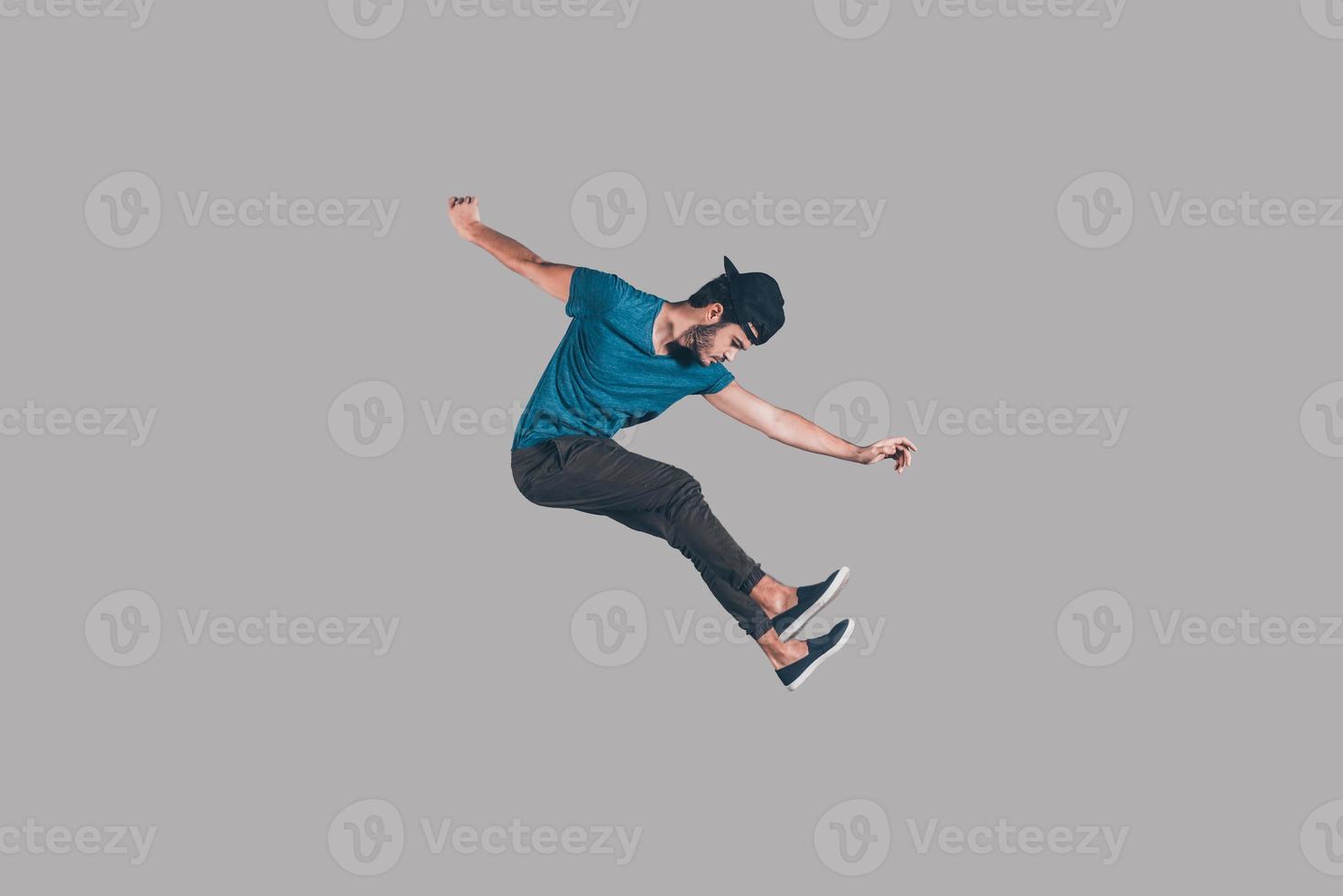 vrijheid in elke Actie. in de lucht schot van knap jong Mens in pet jumping en gebaren tegen achtergrond foto