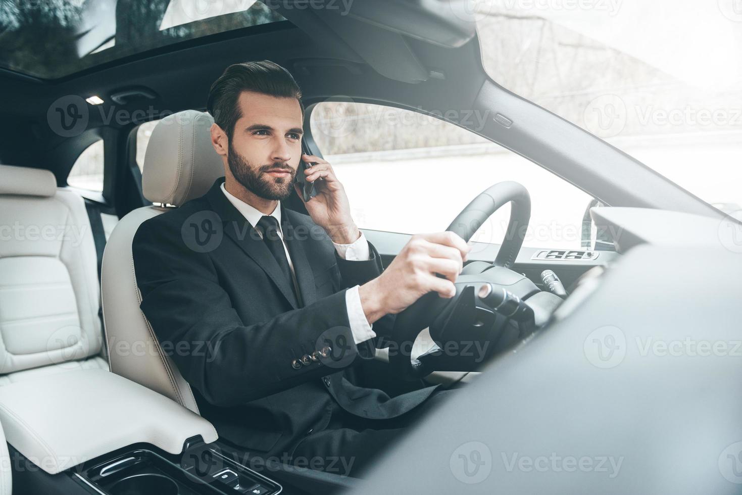 belangrijk telefoon praten. knap jong zakenman pratend Aan zijn slim telefoon met echt gezicht terwijl het rijden de auto foto