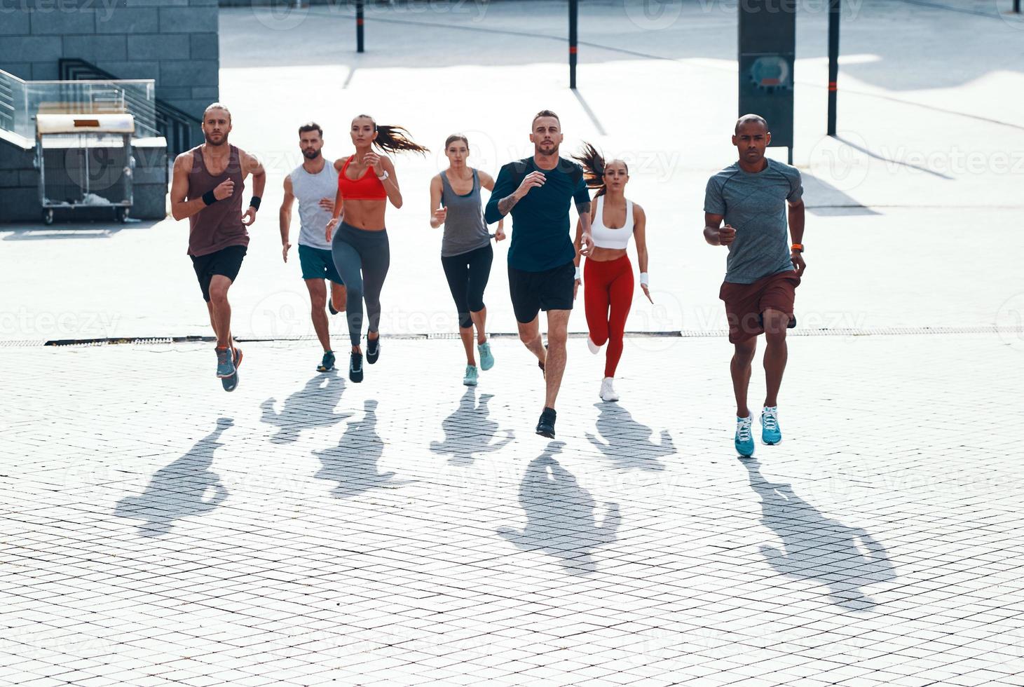 vol lengte top visie van mensen in sport- kleding jogging terwijl oefenen Aan de trottoir buitenshuis foto