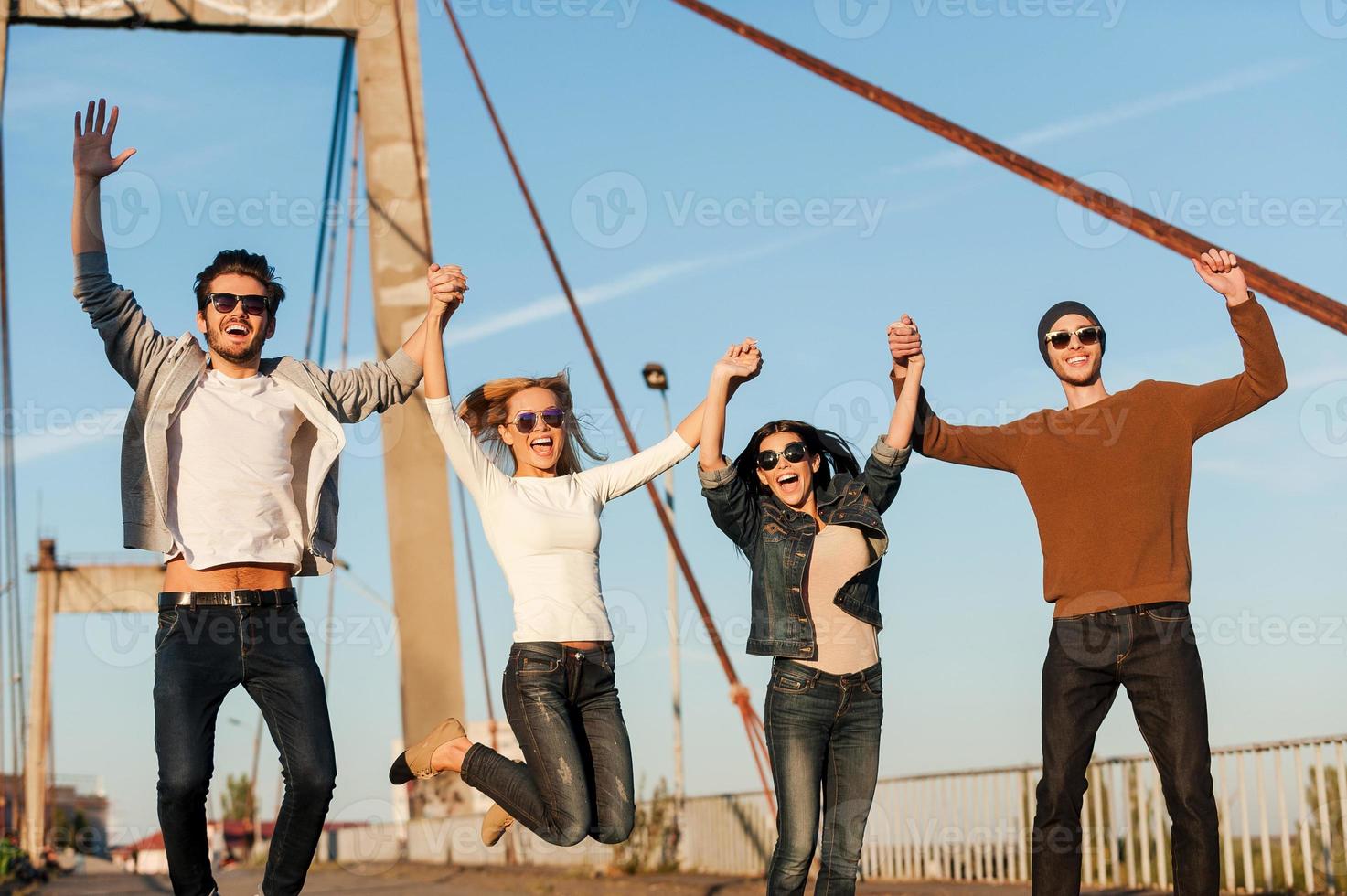 wij zijn gelukkig groep van jong vrolijk mensen Holding handen en jumping foto