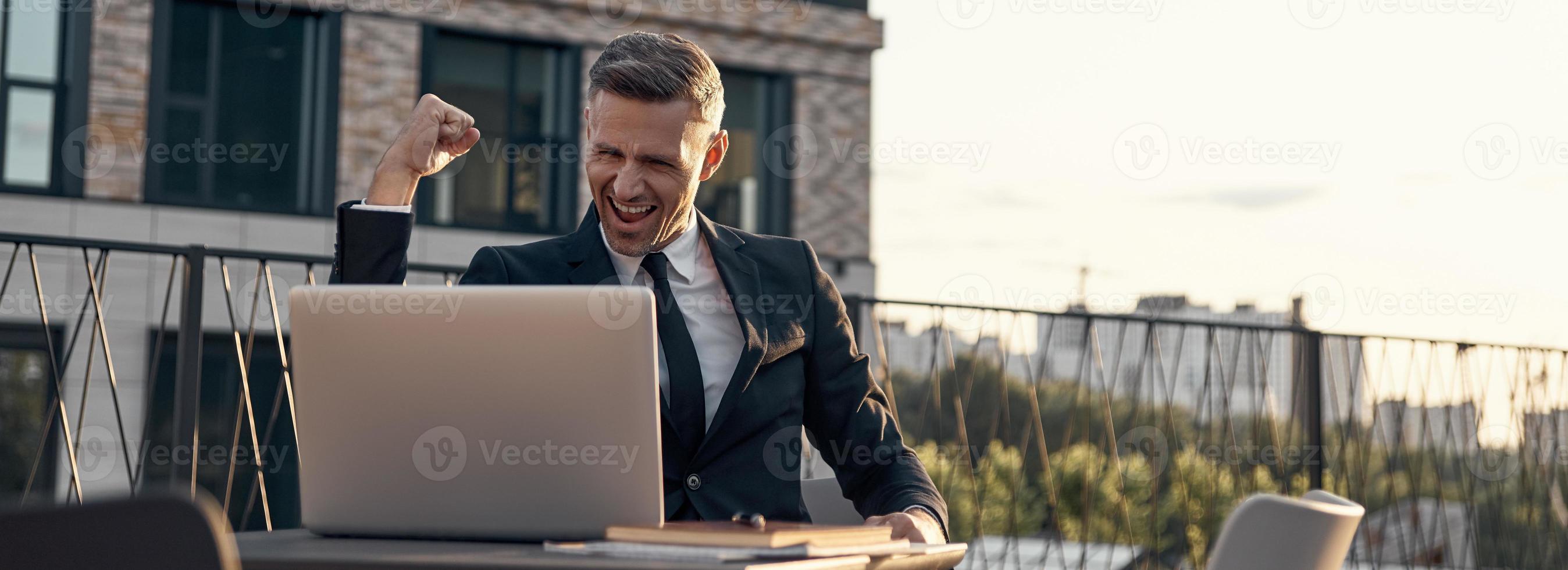 vrolijk volwassen zakenman hebben video telefoontje Aan laptop terwijl zittend in cafe buitenshuis foto