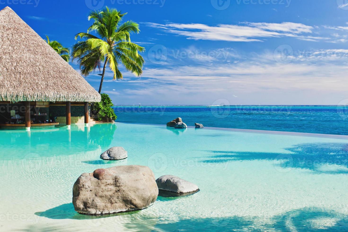 een overloopzwembad met kunstmatig strand en blauwe oceaan foto