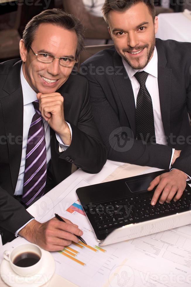 bedrijf mensen. top visie van twee bedrijf mensen in formele kleding glimlachen Bij camera terwijl werken Aan laptop foto