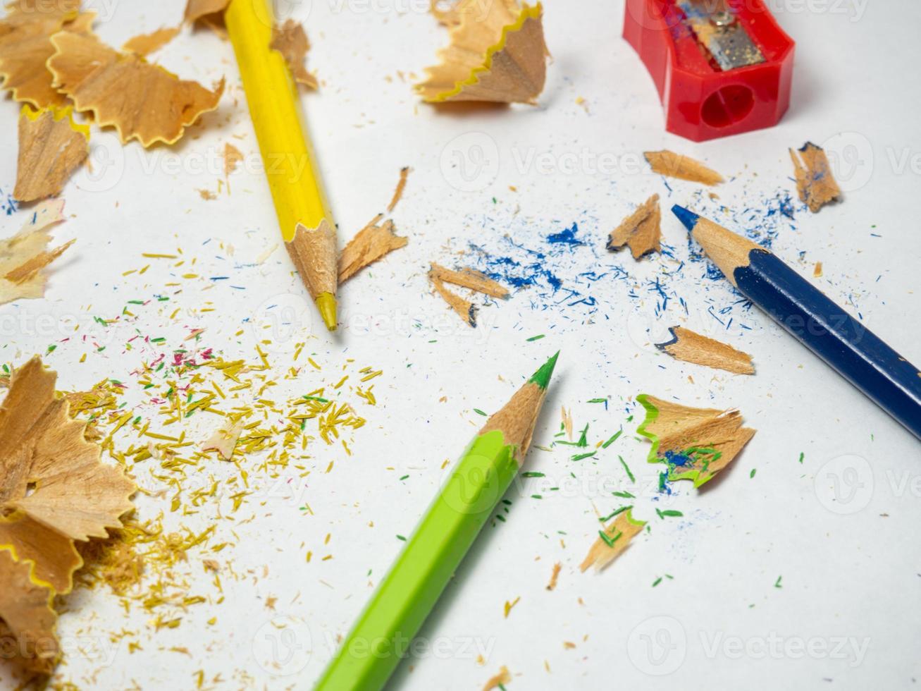 school- benodigdheden. potlood verscherping. veelkleurig potloden Aan een wit achtergrond. hout schaafsel. de werkwijze van voorbereidingen treffen voor werk. creatief knoeien foto