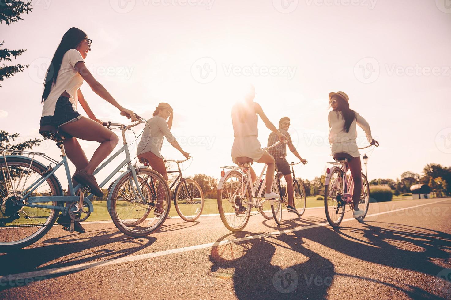 genieten van vrijheid. laag hoek visie van jong mensen rijden fietsen langs een weg en op zoek gelukkig foto