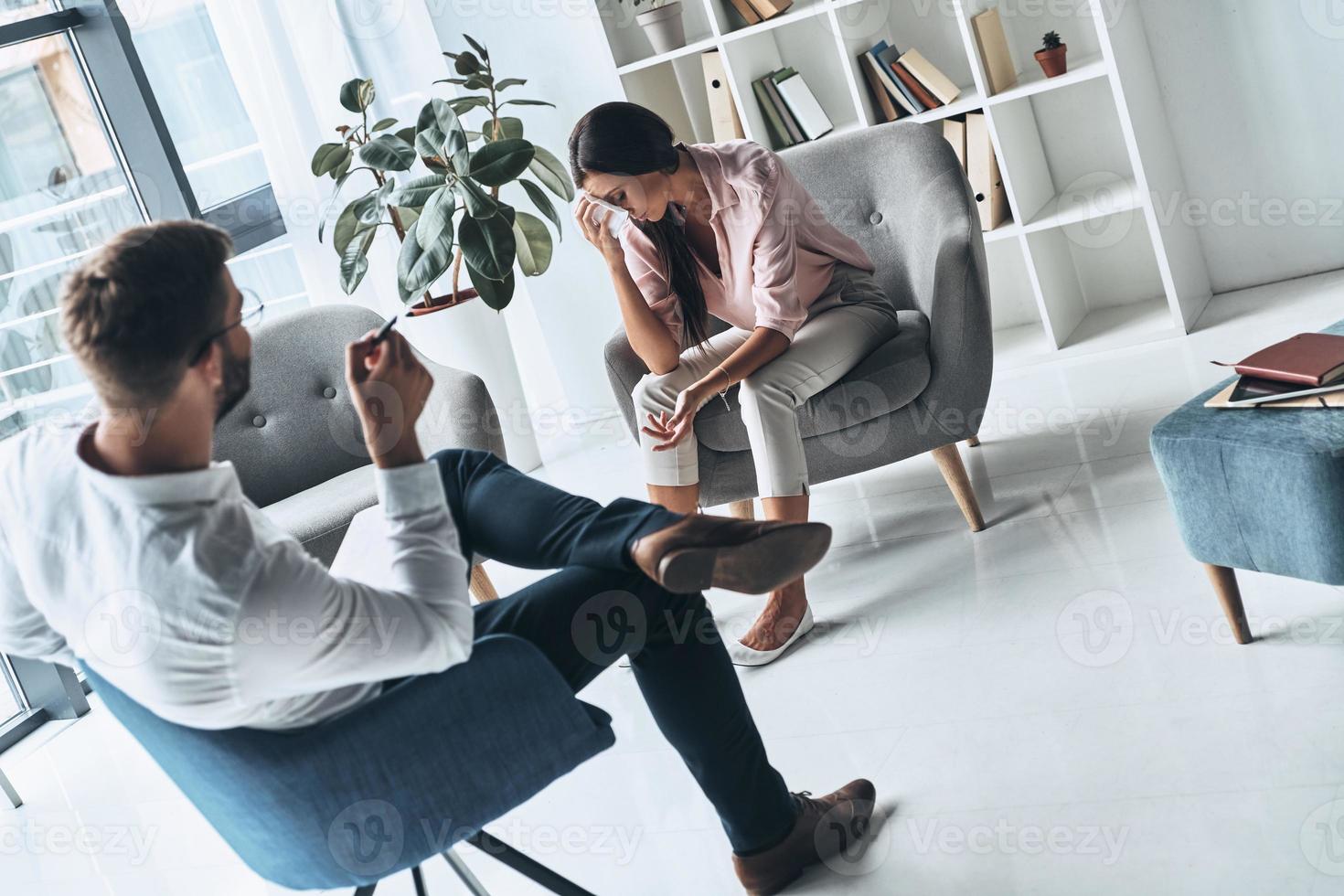 ze is hebben een moeilijk tijd. jong gefrustreerd vrouw oplossen haar mentaal problemen terwijl zittend Aan de behandeling sessie met psycholoog foto