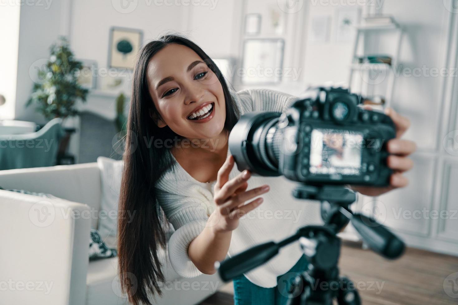 controle media apparatuur. aantrekkelijk jong vrouw aanpassen video camera en glimlachen terwijl maken nieuw video voor haar blog foto