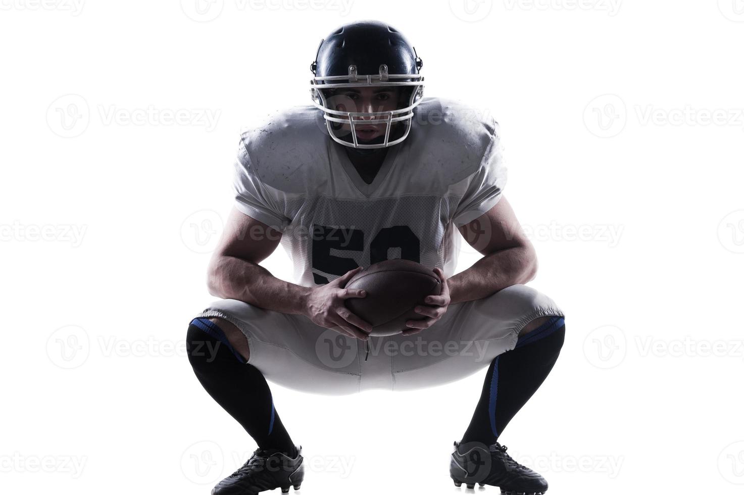 ik hebben Nee Gelijk in deze sport. Amerikaans Amerikaans voetbal speler Holding bal en vervelend helm terwijl zittend tegen wit achtergrond foto