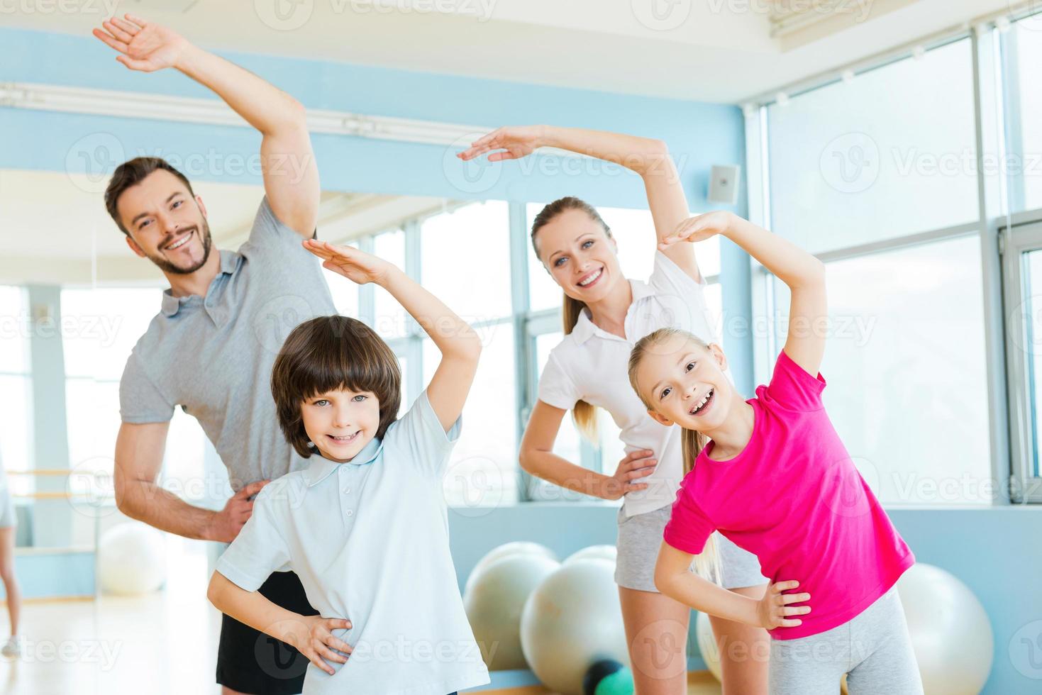 familie oefenen. gelukkig sportief familie aan het doen uitrekken opdrachten in sport- club foto