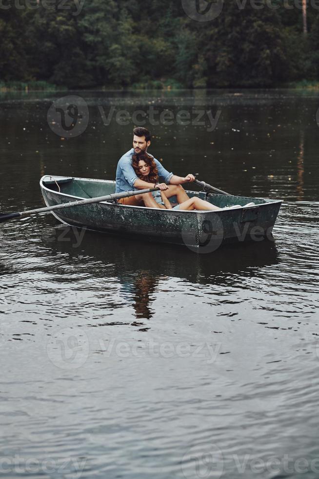 heel momenten samen. mooi jong paar omarmen terwijl genieten van romantisch datum Aan de meer foto