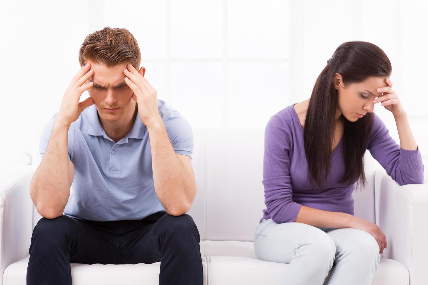 verhouding moeilijkheden. depressief jong Mens en vrouw zittend dichtbij naar elk andere Aan de bankstel en Holding hoofd in handen foto