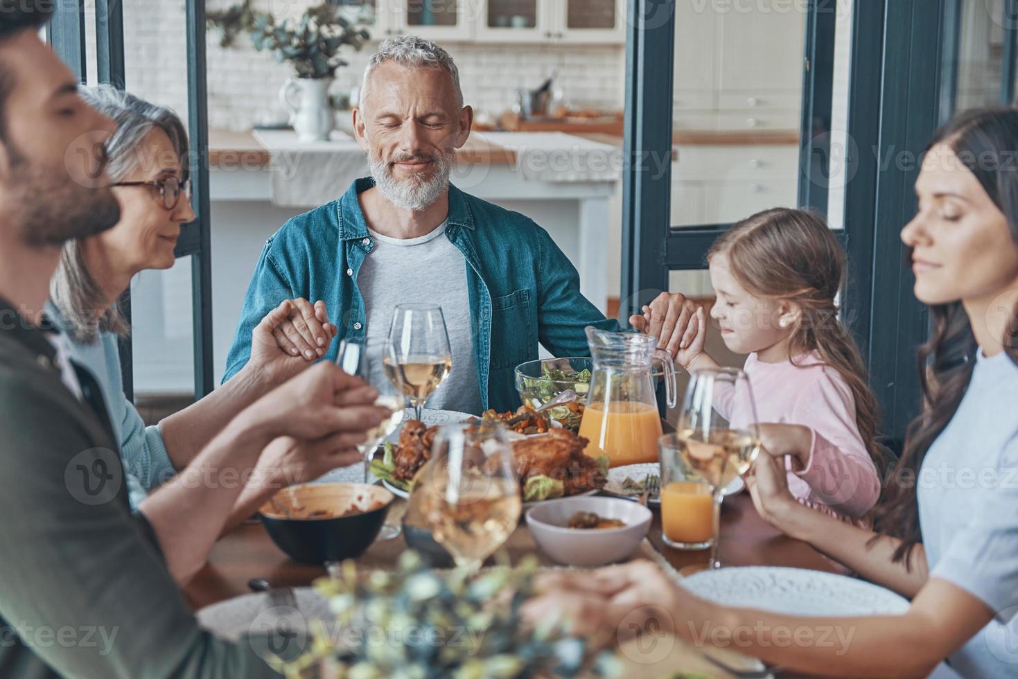 gelukkig meerdere generaties familie Holding handen en bidden voordat hebben avondeten foto