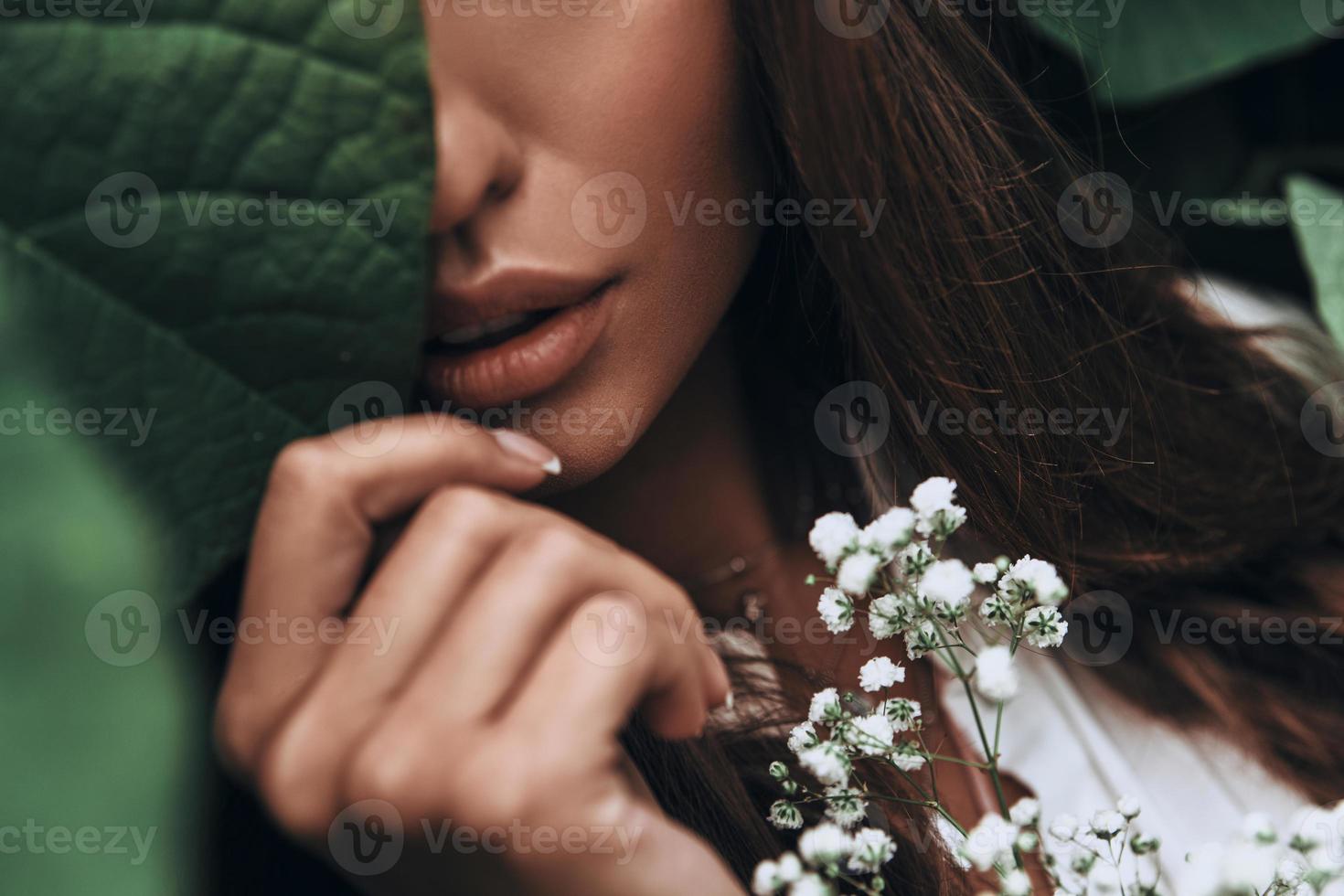 zuiver schoonheid. detailopname van jong vrouw aanraken blad met hand- terwijl staand buitenshuis foto