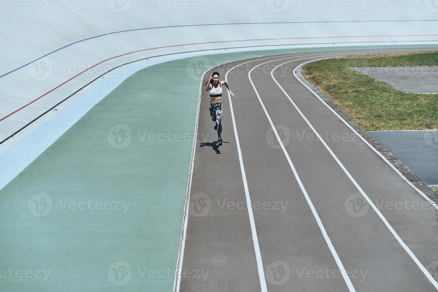 haar het beste snelheid. vol lengte top visie van jong vrouw in sport- kleding jogging terwijl oefenen buitenshuis foto