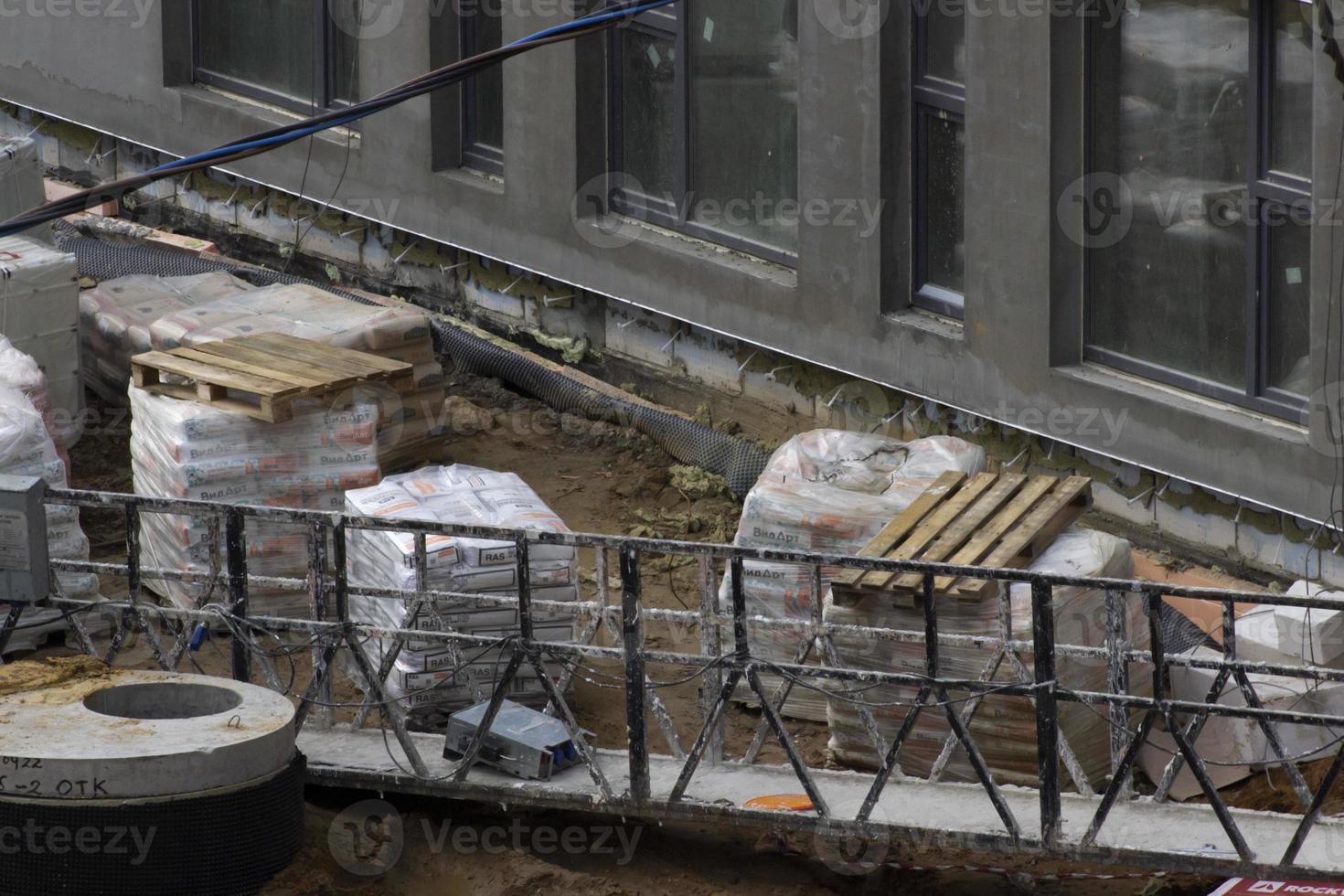 visie van gebouw plaats, speciaal uitrusting en materialen, horizontaal foto. gebouw bouw werkwijze, afval, houten pallets. vuil brug, zand, muur met ramen foto