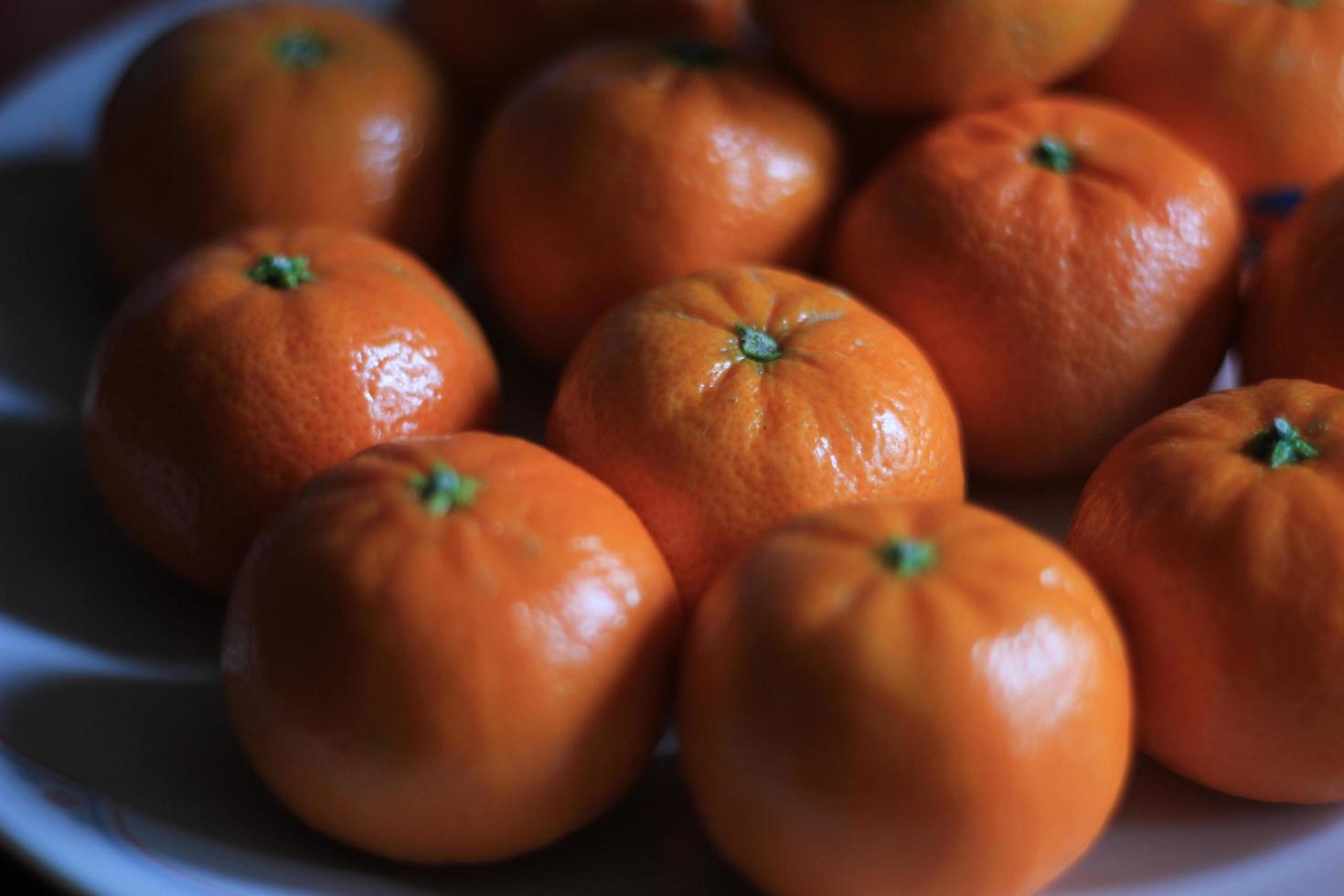 klein sinaasappels zijn geplaatst in een wit bord Aan de oranje tafel. foto