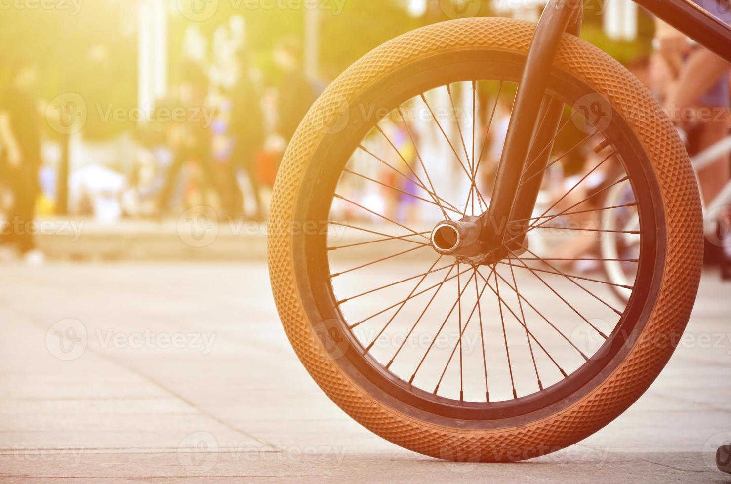een bmx fiets wiel tegen de backdrop van een wazig straat met wielersport ruiters. extreem sport- concept foto