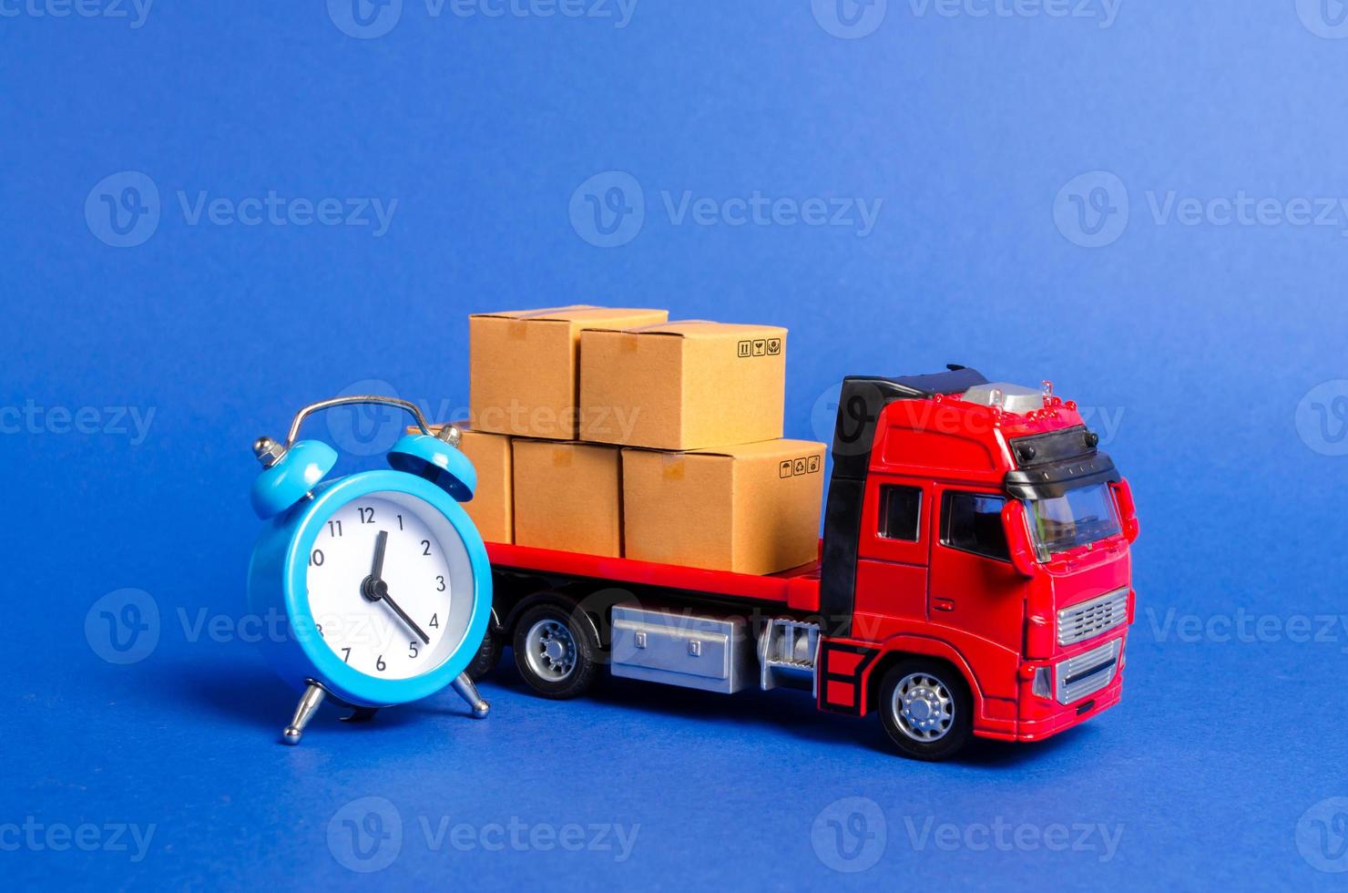 een rood vrachtauto met karton dozen en een blauw alarm klok. uitdrukken levering in kort tijd concept. tijdelijk opslag, beperkt aanbod en korting. optimalisatie van levering logistiek. vervoer bedrijf foto