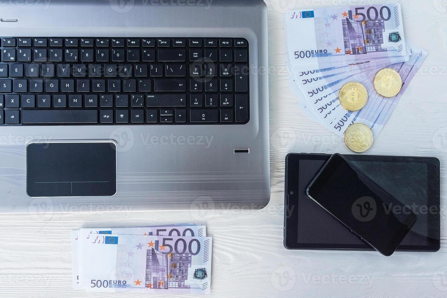 laptop met contant geld en bitcoin foto