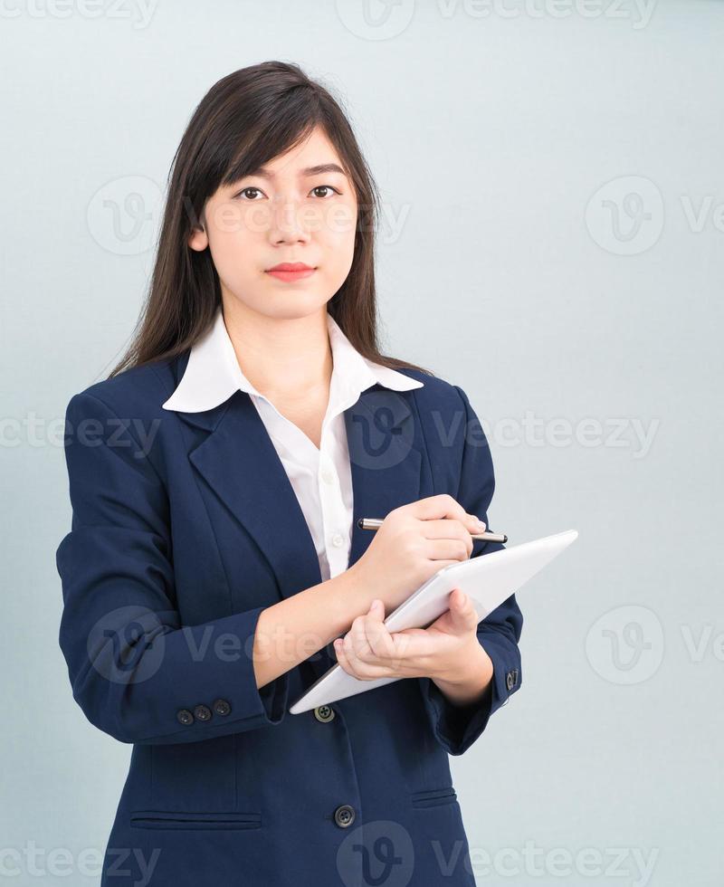 vrouw in pak gebruik makend van digitaal tablet Aan grijs achtergrond foto