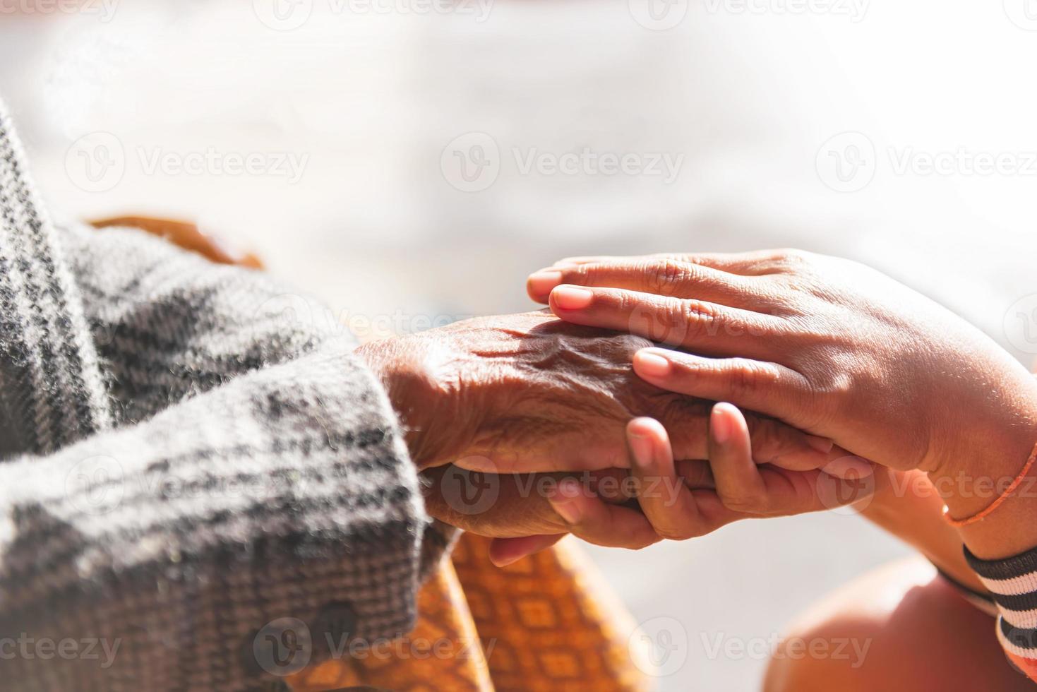 de dochter getroost de oud vrouw en verheven haar hand- in de buurt. gesprek dat is een sterk verhouding mededogen en sympathie ondersteuning gedurende een moeilijk leven. foto