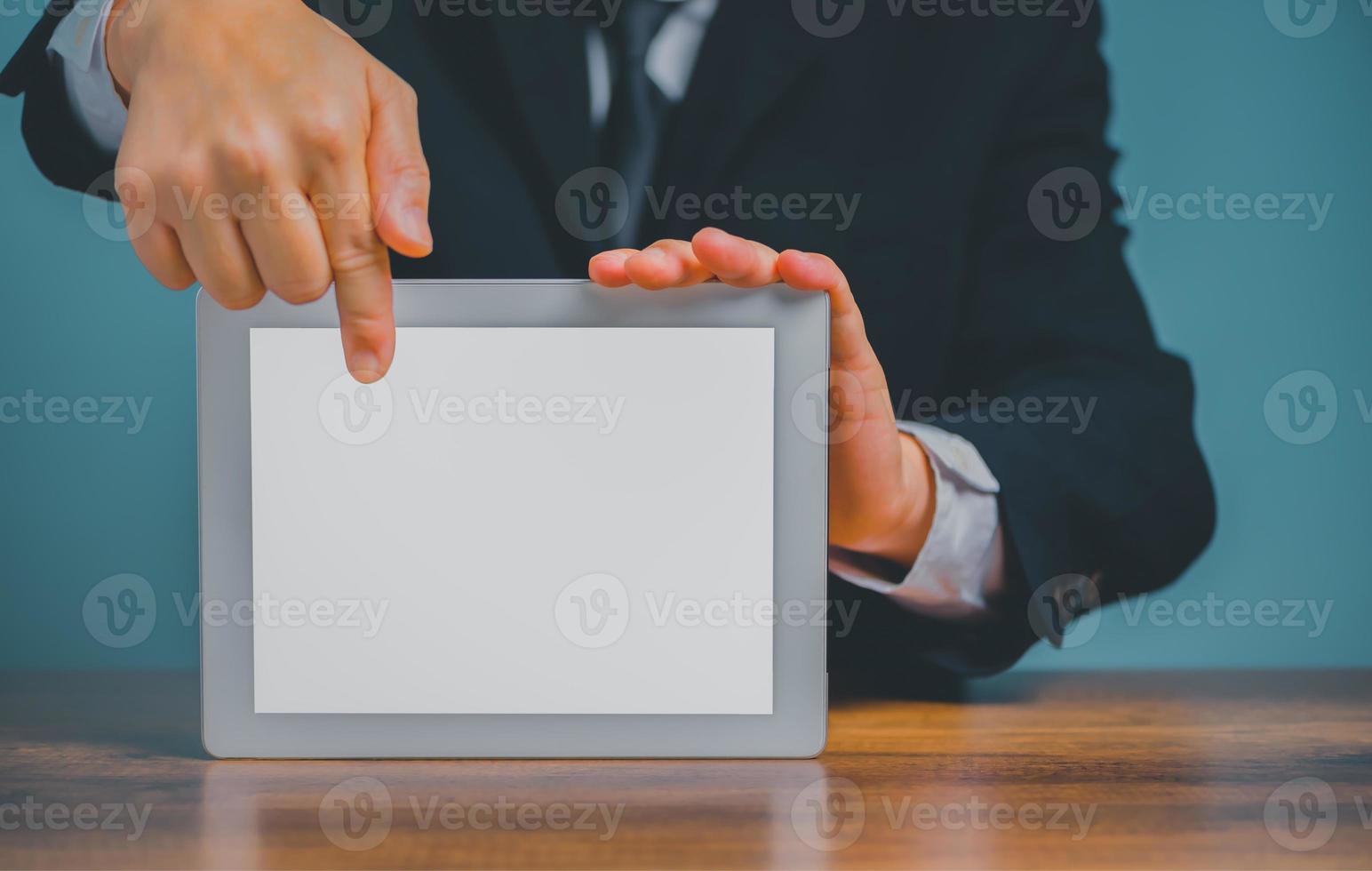 bedrijf Mens Holding en richten Aan digitaal tablet Aan de bureau met geïsoleerd wit achtergrond en kopiëren ruimte. foto