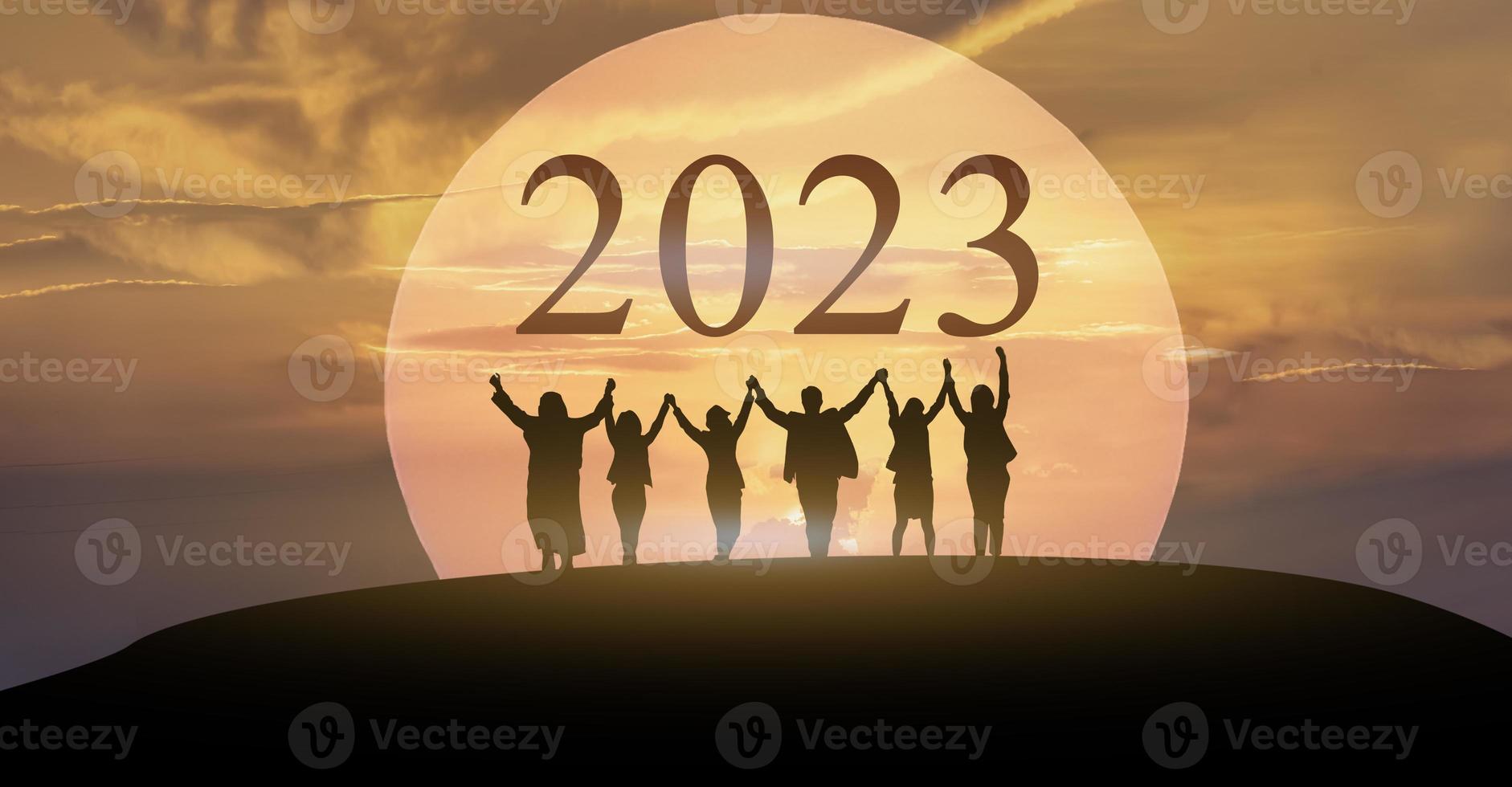 gelukkig nieuw jaar 2023, houden vechten samen, silhouet van 2023 brieven Aan de berg met bedrijf mensen verheven armen in samenspel concept Bij zonsopkomst. foto