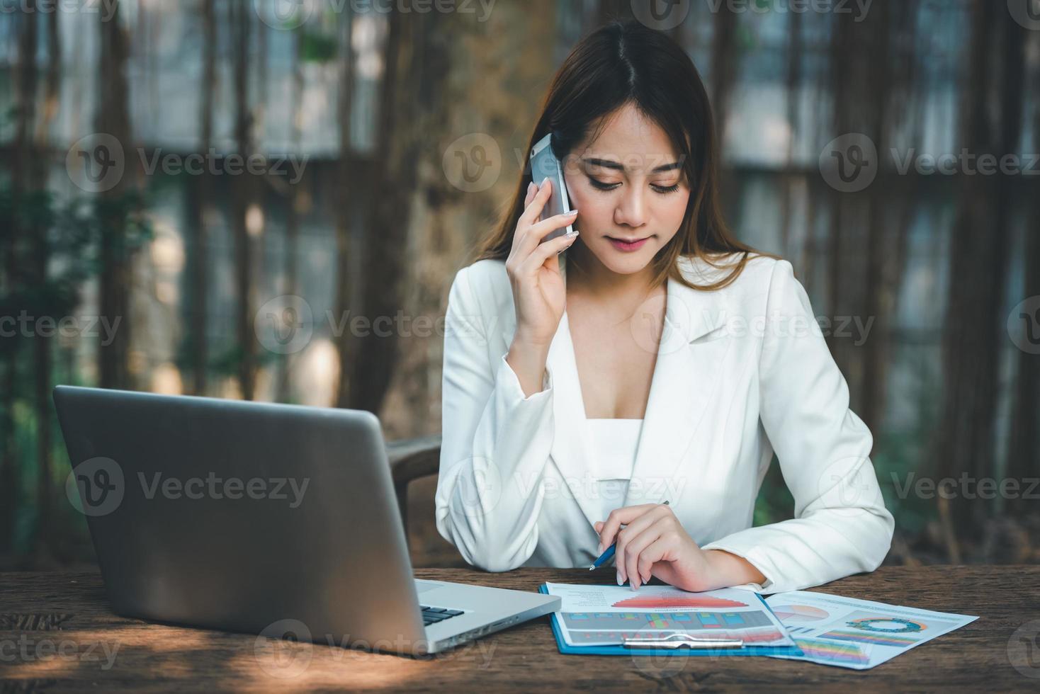 gelukkig jong Aziatisch uitvoerend bedrijf vrouw in afzet werken met laptop computer, pratend Aan mobiel telefoon en vragen over iets ,zakelijk communicatie concept. foto