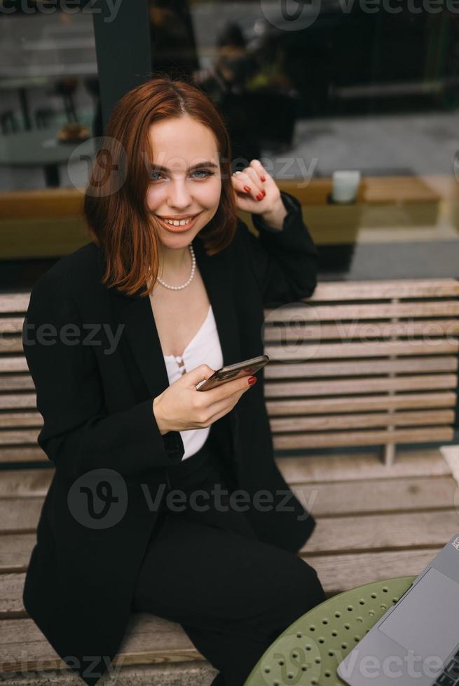 jong vrouw toepassingen de telefoon Bij de straat cafe foto
