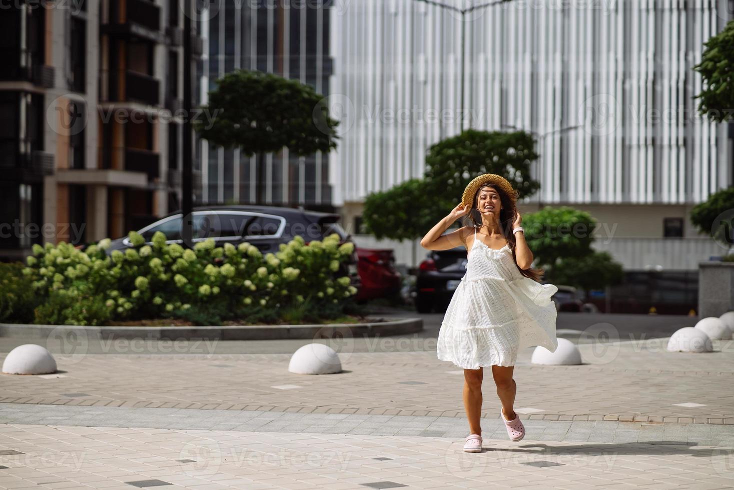 mooi mooi vrouw in wit jurk wandelen Bij stad straat foto