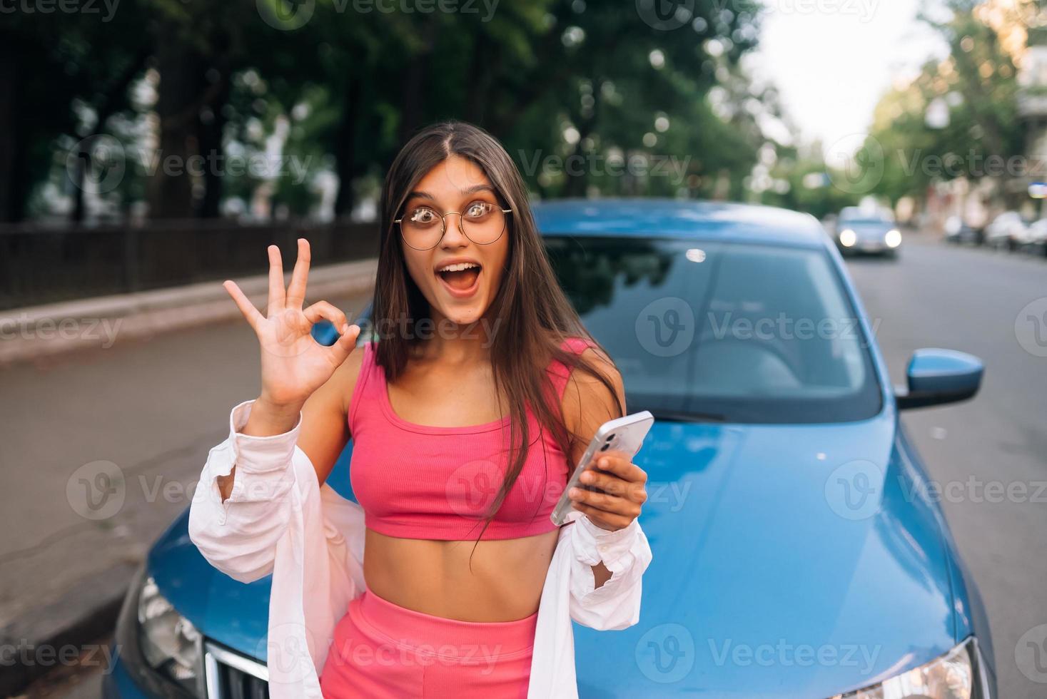 vrouw gebruik makend van mobiel telefoon in de buurt auto Bij de straat foto