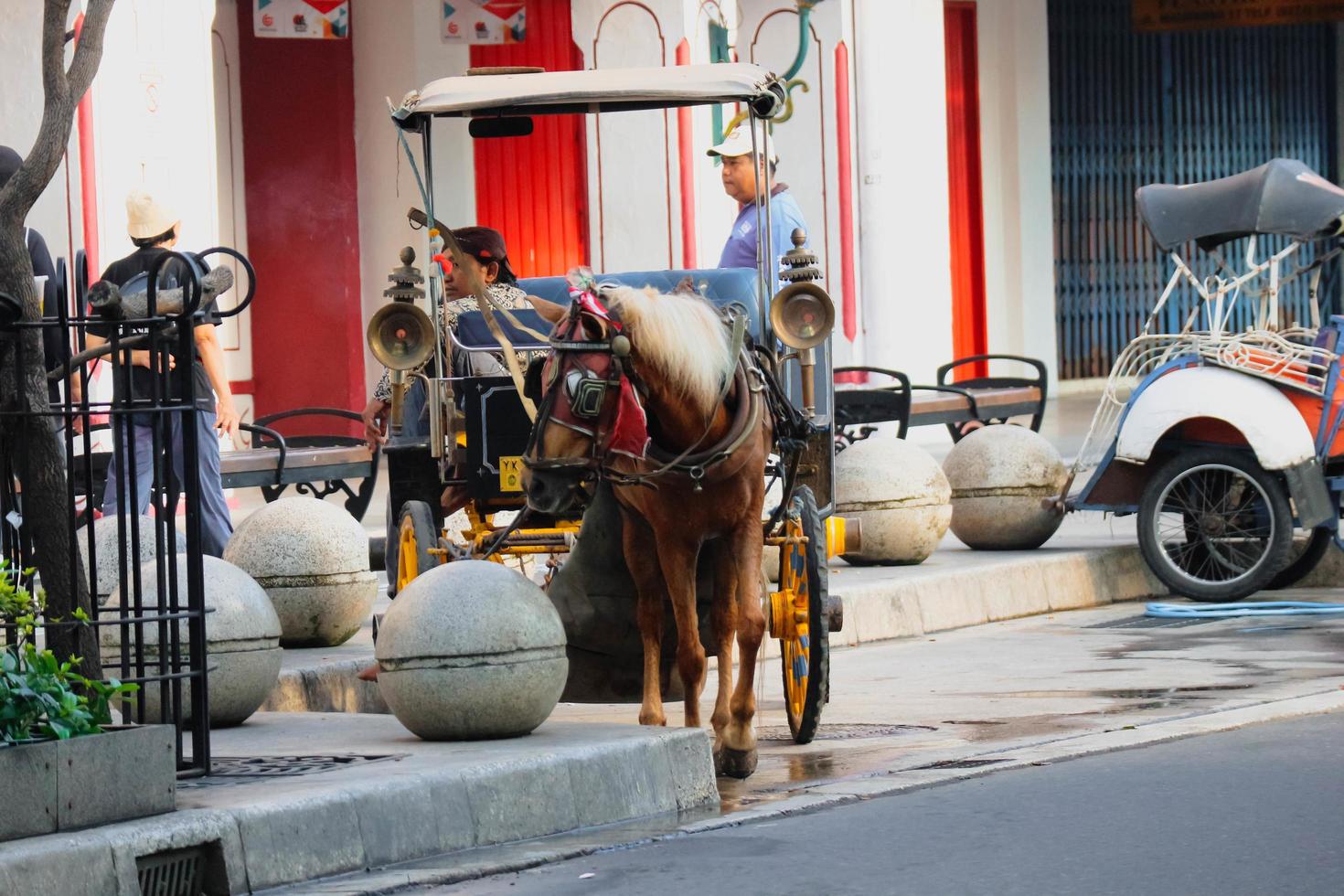 yogakarta, Indonesië Aan oktober 23, 2022. andong of door paarden getrokken vervoer met haar koetsier geparkeerd Aan jalan malioboro, aan het wachten voor passagiers. foto