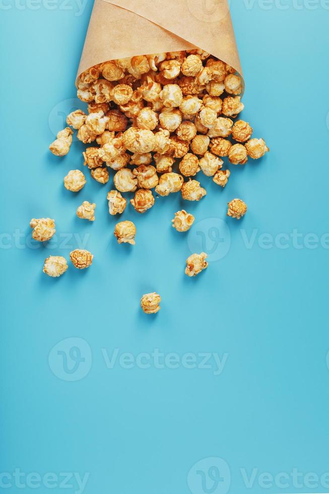 popcorn in karamel glazuur in een papier envelop Aan een blauw achtergrond. foto