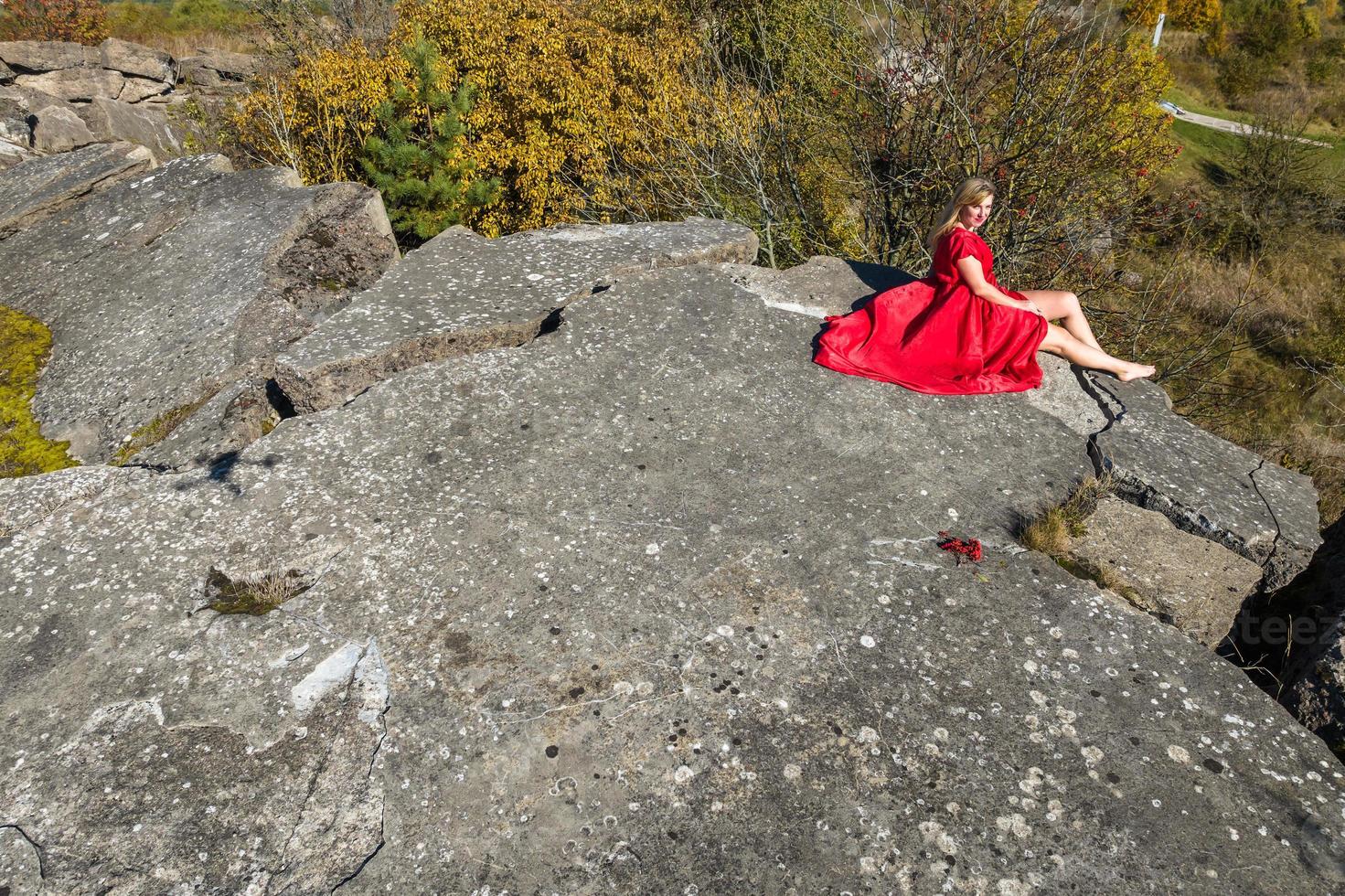 antenne visie Aan meisje in rood jurk Aan rots of beton geruïneerd structuur foto