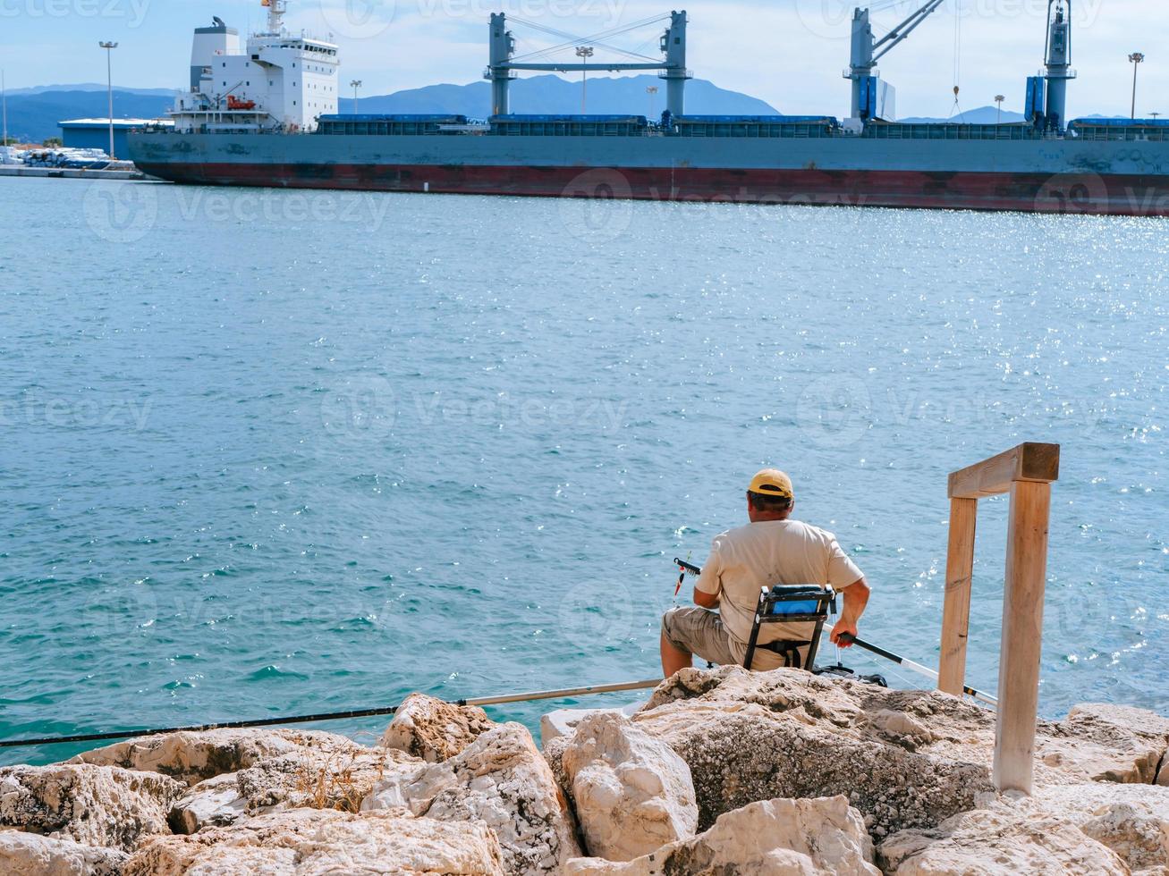 Mens zittend Aan een visvangst plaats in een haven foto