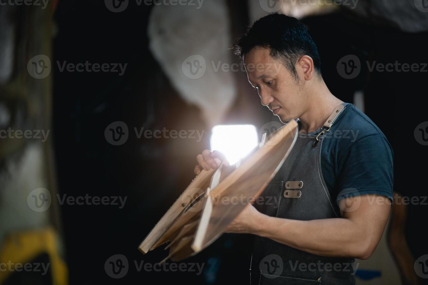 gitaar makers Aziatisch Mens maken akoestisch gitaren in laboratorium. Aziatisch gitaar maker bouwt hoog kwaliteit gitaren voor muzikanten handgemaakt gitaar winkel. werken prima houtmuziek, traditie, oude ambachten. foto