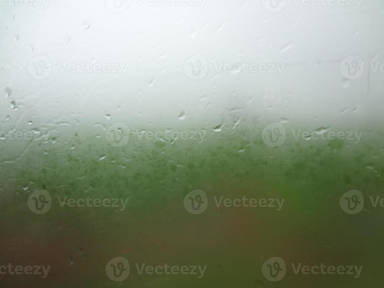 venster glas met condensatie hoog vochtigheid , groot druppels stromen naar beneden , groen natuurlijk water laten vallen achtergrond. foto