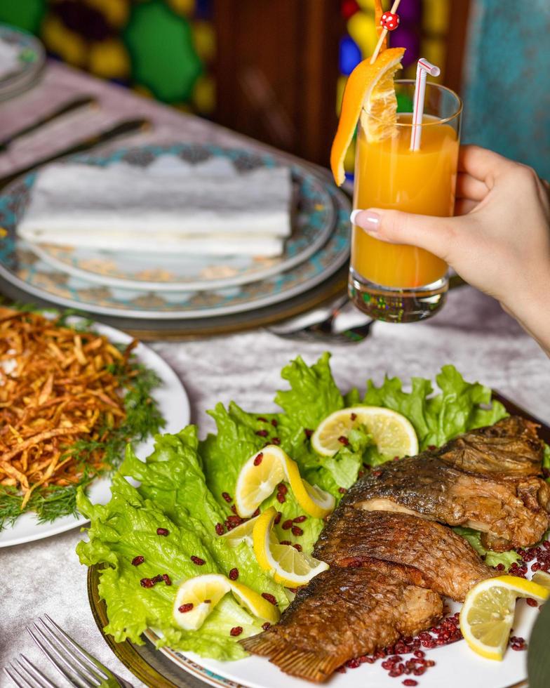 vrouw een hele gegrilde vis met citroen eten foto