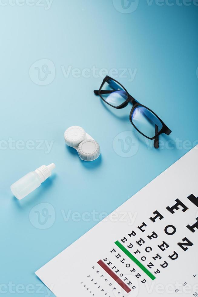 bril met contact lenzen, druppels en een optometrist oog test tabel Aan een blauw achtergrond. foto