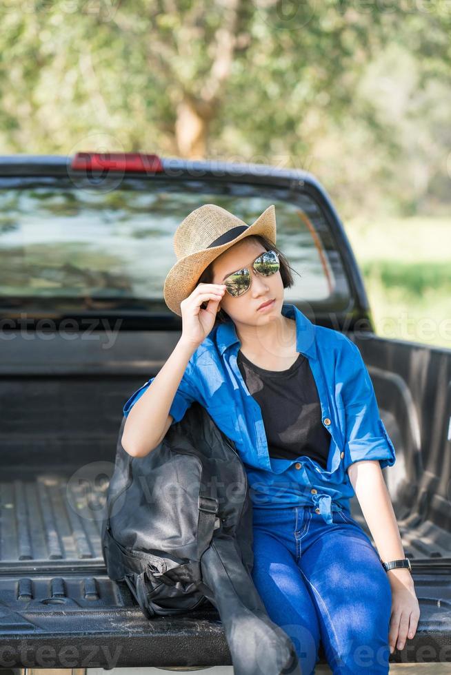 vrouw slijtage hoed en dragen haar gitaar zak Aan oppakken vrachtauto foto