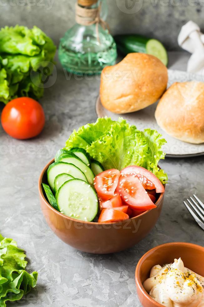 vers groente kom met komkommer, tomaat en sla Aan de tafel Bij huis. verticaal visie. detailopname foto