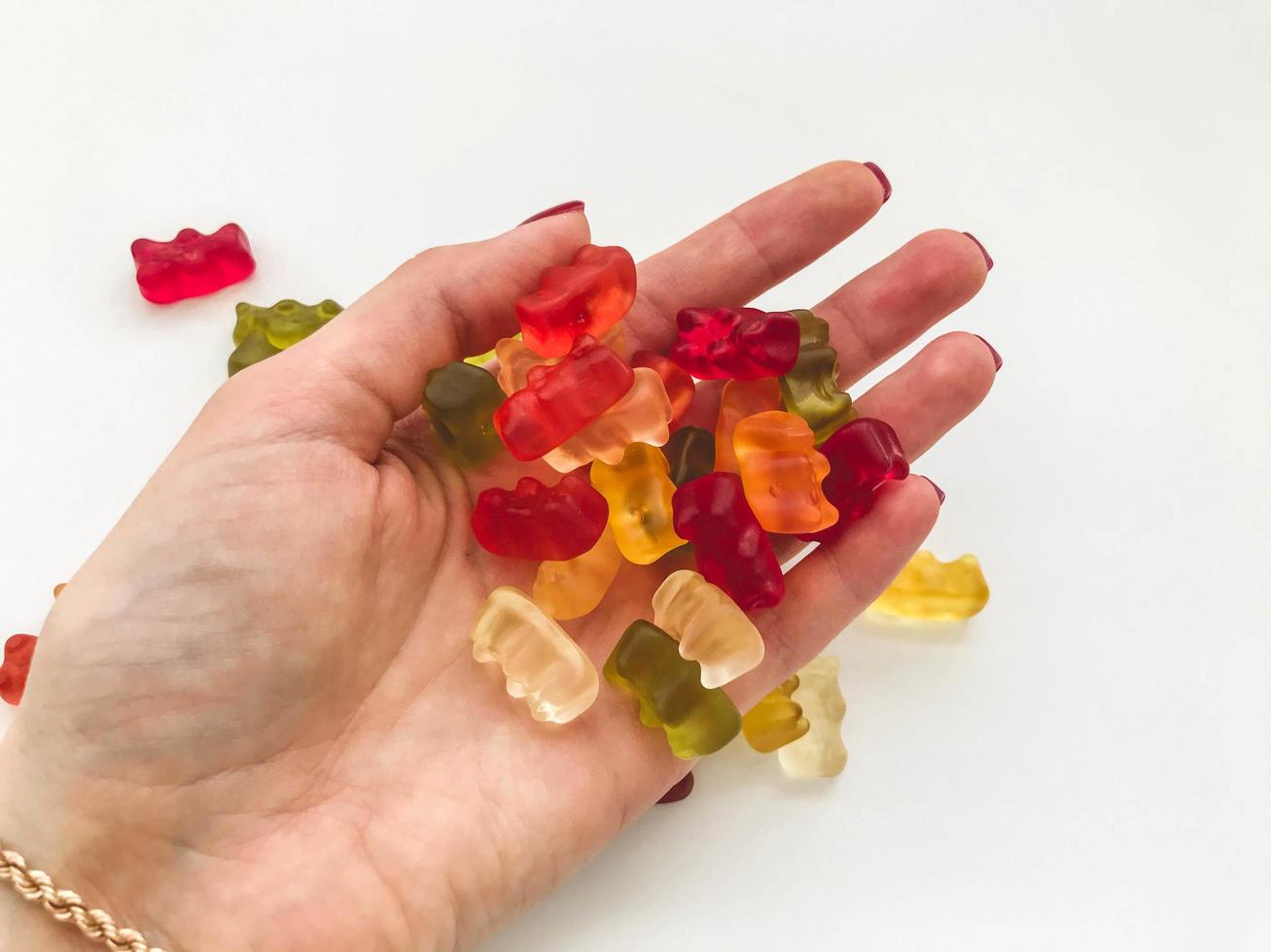 kleverig veelkleurig bears liggen Aan een hand- met een goud armband. gekleurde bears gemaakt van gelatine, calorierijk nagerecht. behandelt voor kinderen en volwassenen. smakelijk snoep foto